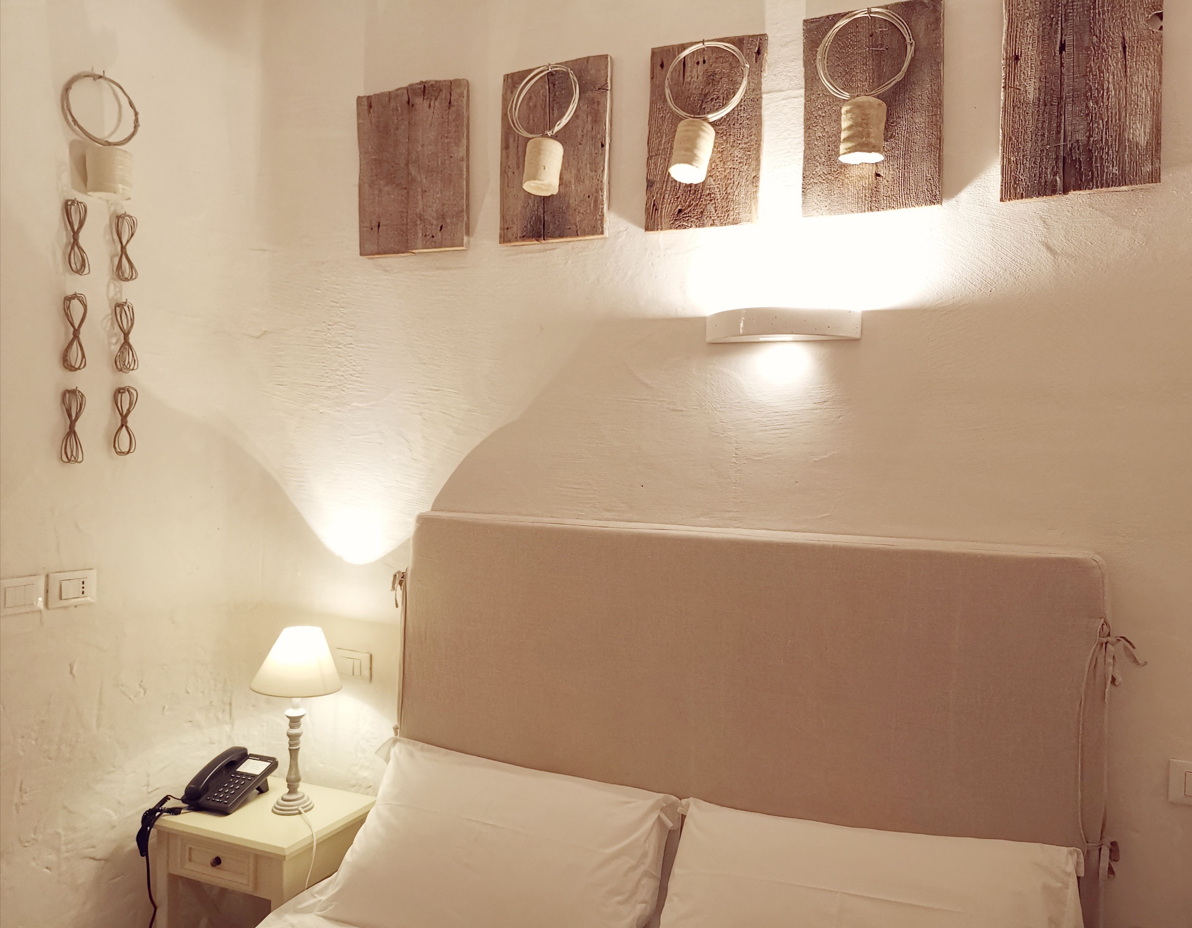 Une chambre d’hôtel équipée d’un lit, d’une lampe de chevet, d’un téléphone et de décorations murales.