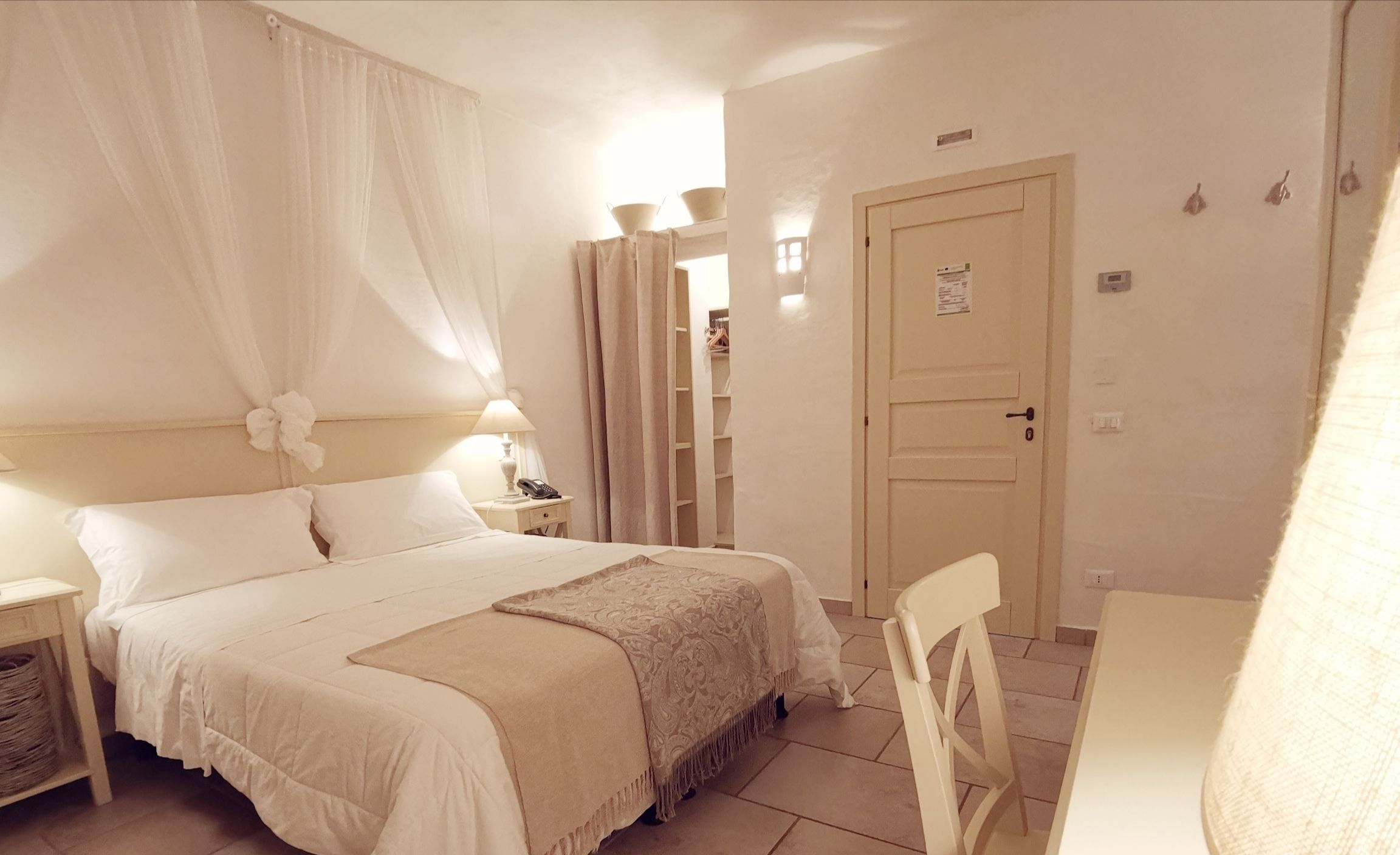 A bedroom with a bed, bedside table, lamp, and a chair.