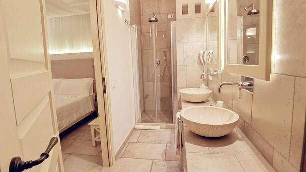 A modern bathroom with a glass-enclosed shower, a round marble sink, and a large mirror. - Le Nicchie Guest House (Lucera)