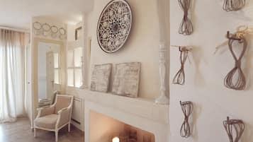 Una habitación con chimenea, una silla blanca y un espejo.
