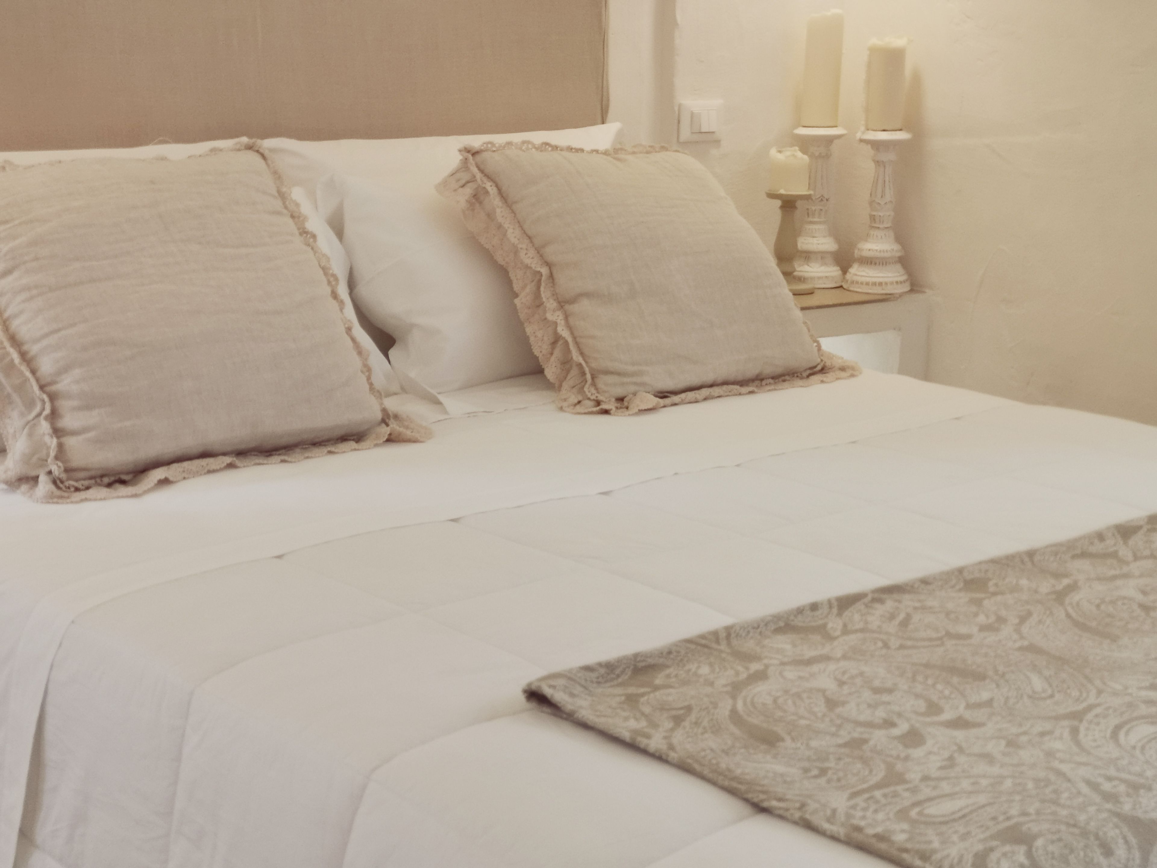 Una cama bien hecha con dos almohadas y un cojín decorativo.