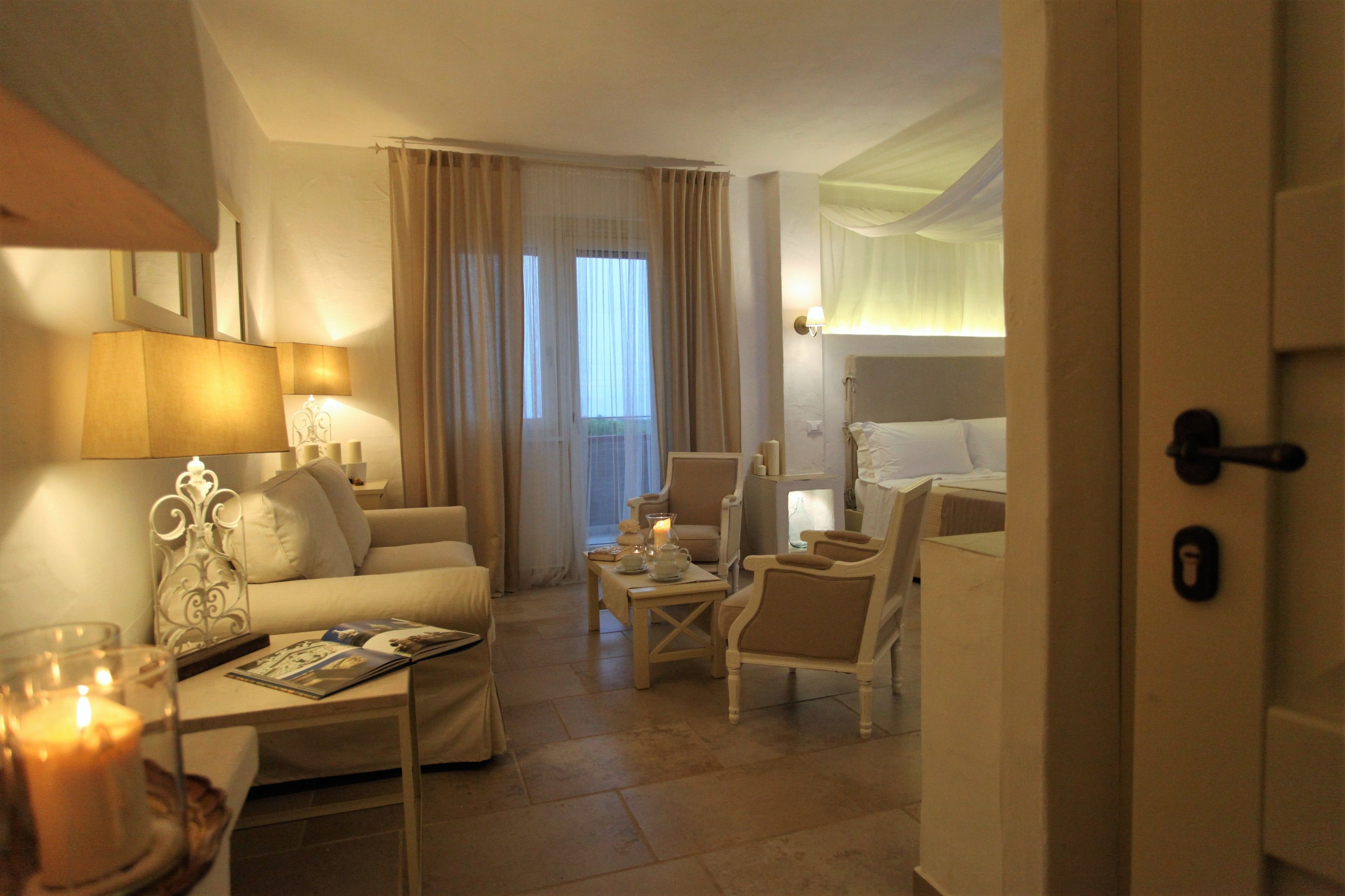 A hotel room with a sofa, armchairs, a coffee table, and a bed.