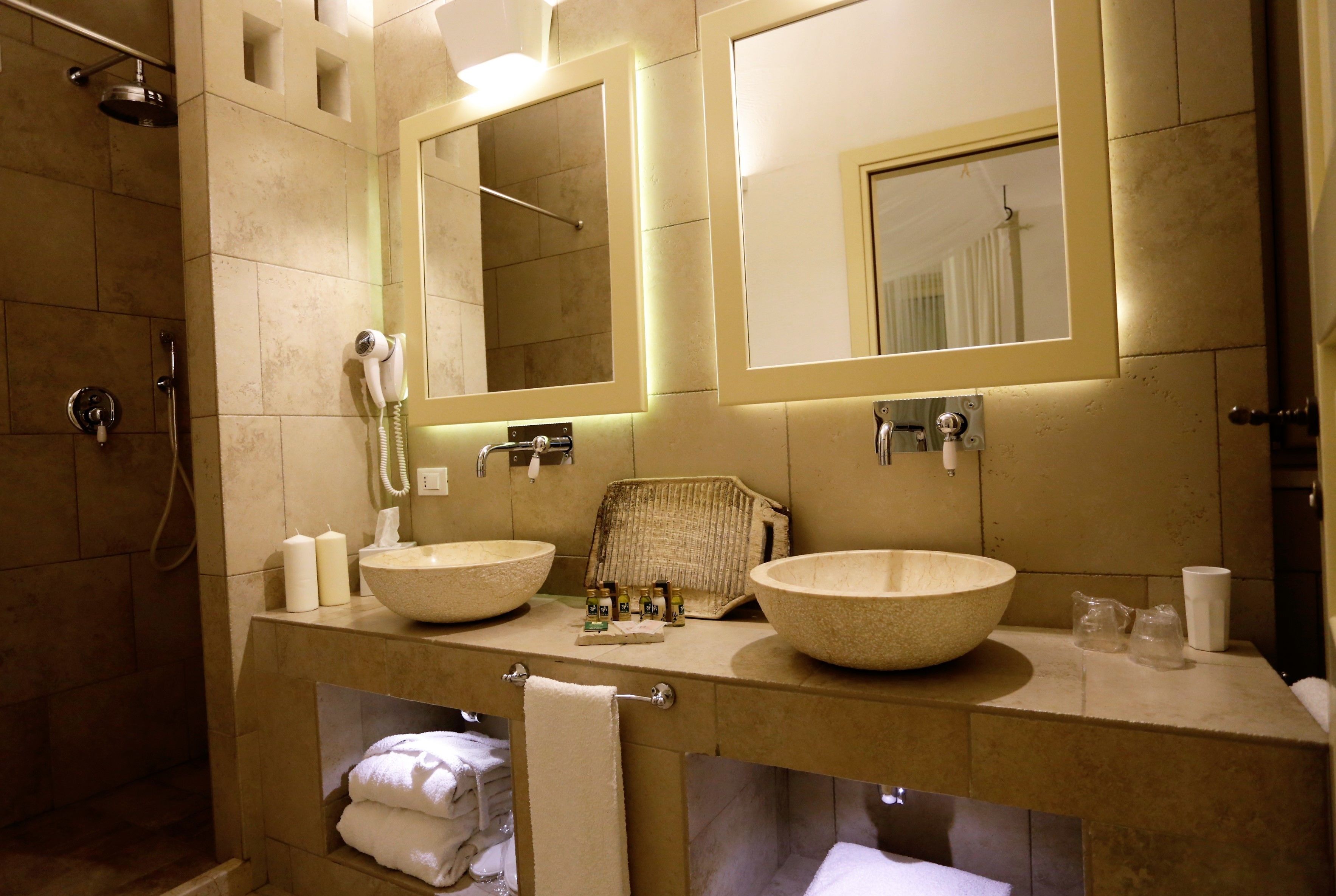 Une salle de bain avec deux grands lavabos de couleur beige, un sèche-cheveux et un porte-serviettes.