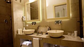 Une salle de bain avec deux grands lavabos de couleur beige, un sèche-cheveux et un porte-serviettes.