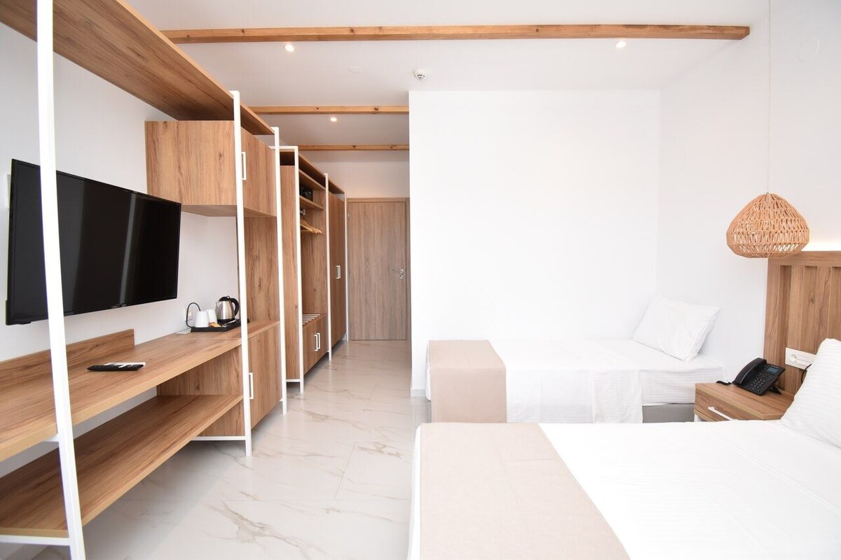 A modern hotel room with a bed, bedside table, TV, and built-in wardrobe.