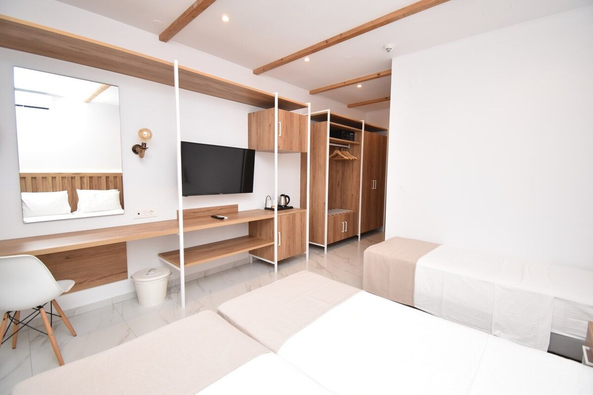 Un dormitorio moderno con cama, televisor, armario y escritorio.