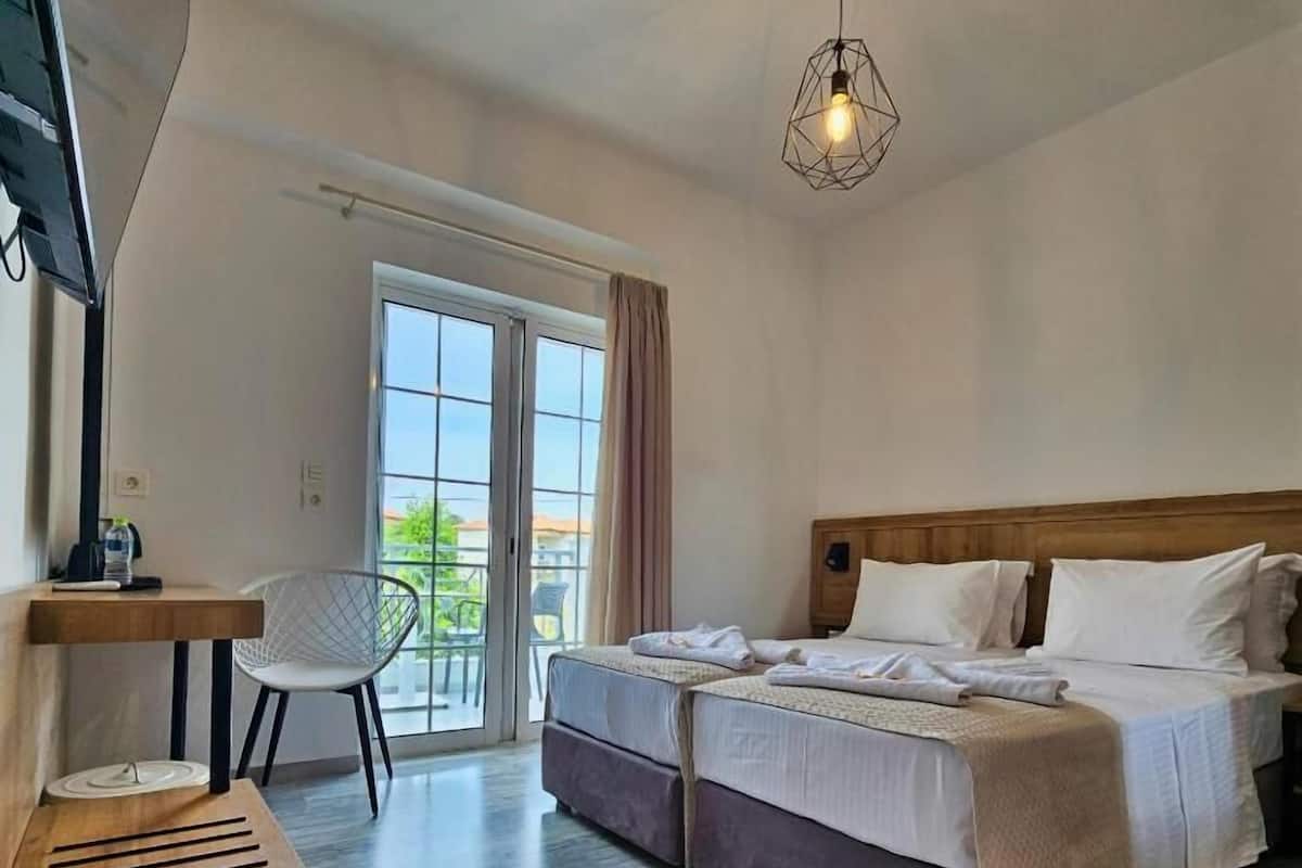 Habitación de hotel con cama, escritorio, silla y un amplio ventanal.