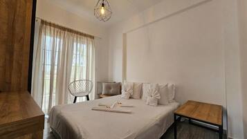 A hotel room with a bed, a wooden nightstand, a chair, and a small table.