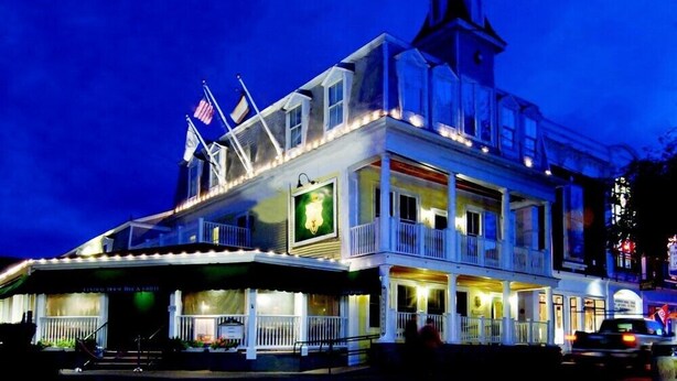 A multi-story building with a balcony, a flag, and a sign.