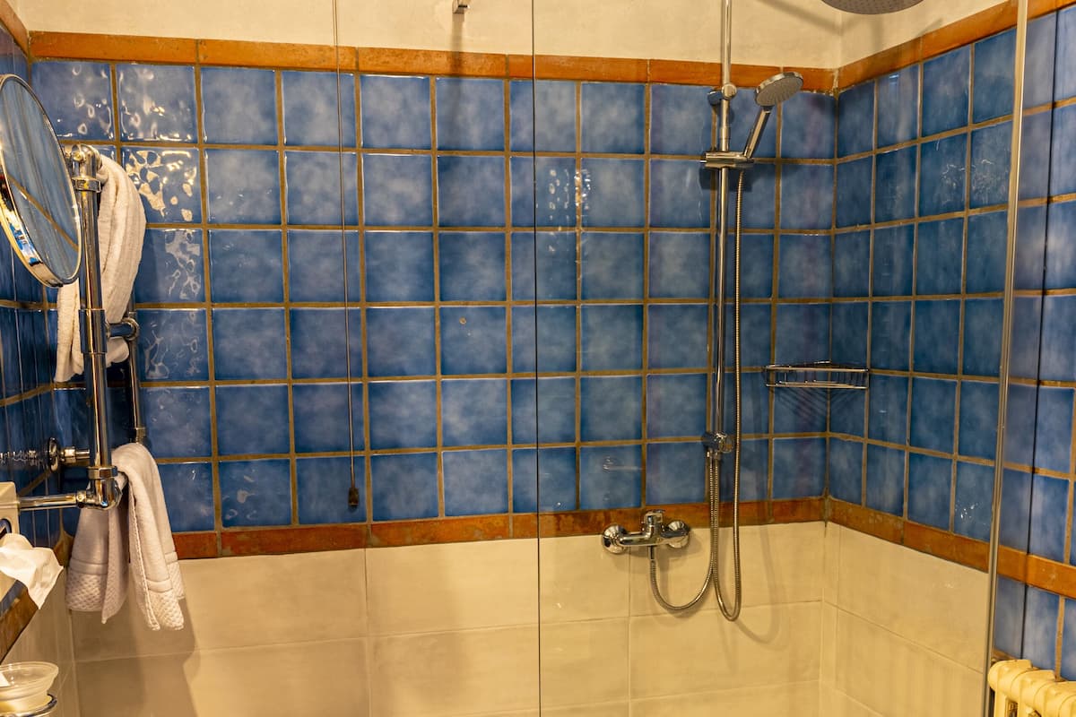A bathroom with a blue sink, a glass shower enclosure, and a tiled wall.