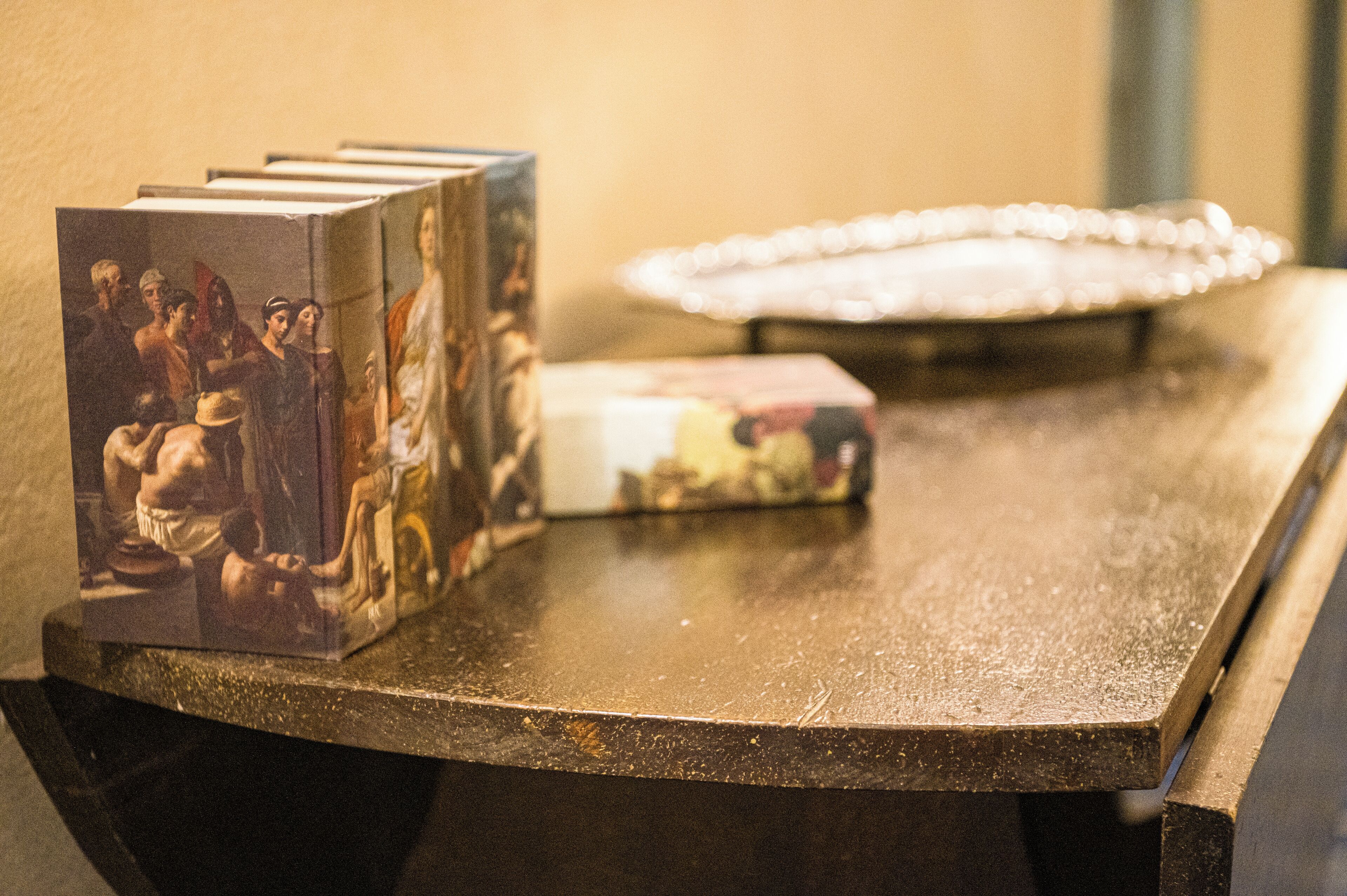Een tafel met een stapel boeken en een decoratief bord.