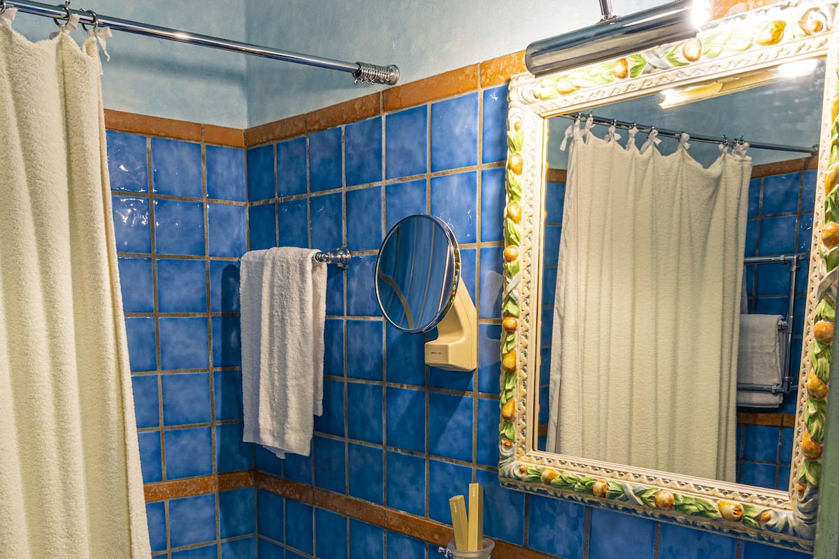 A bathroom with a blue sink, white bathtub, and a mirror with a decorative frame.
