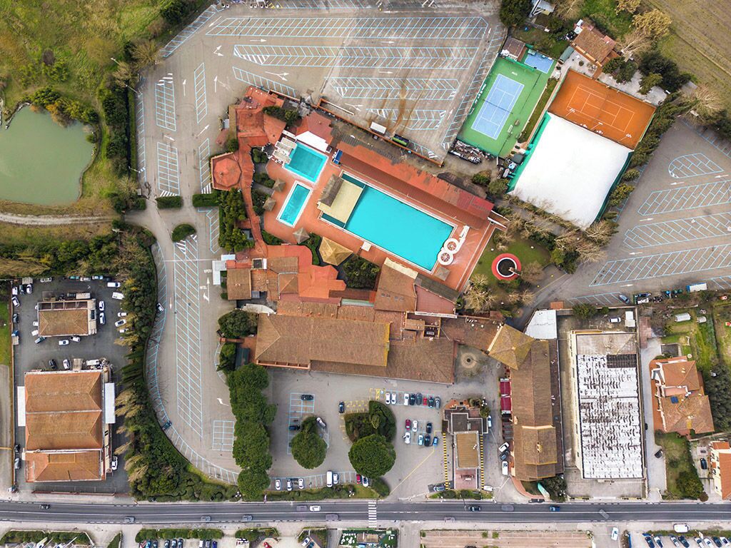 Ein Luftbild eines Komplexes mit Schwimmbad, Tennisplätzen und Parkplatz.