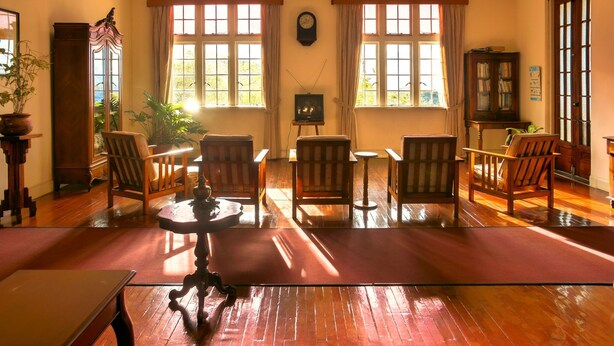 A traditional room with wooden furniture, a clock, and a television.
