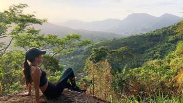 Una persona asseguda sobre una roca amb vista a un paisatge muntanyós.