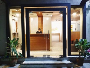 A reception area with a receptionist, a wooden reception desk, and potted plants. - The Southern Cross Hotel (Manila)