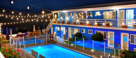 A hotel with a pool, outdoor seating, and string lights.