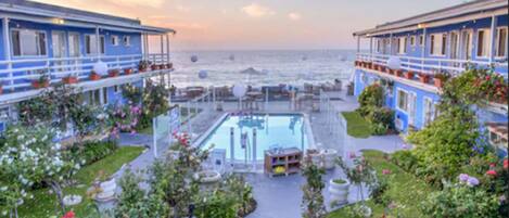 Et hotel med swimmingpool, udendørs siddepladser og havudsigt.