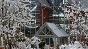 A modern building with large glass windows and a stone chimney.