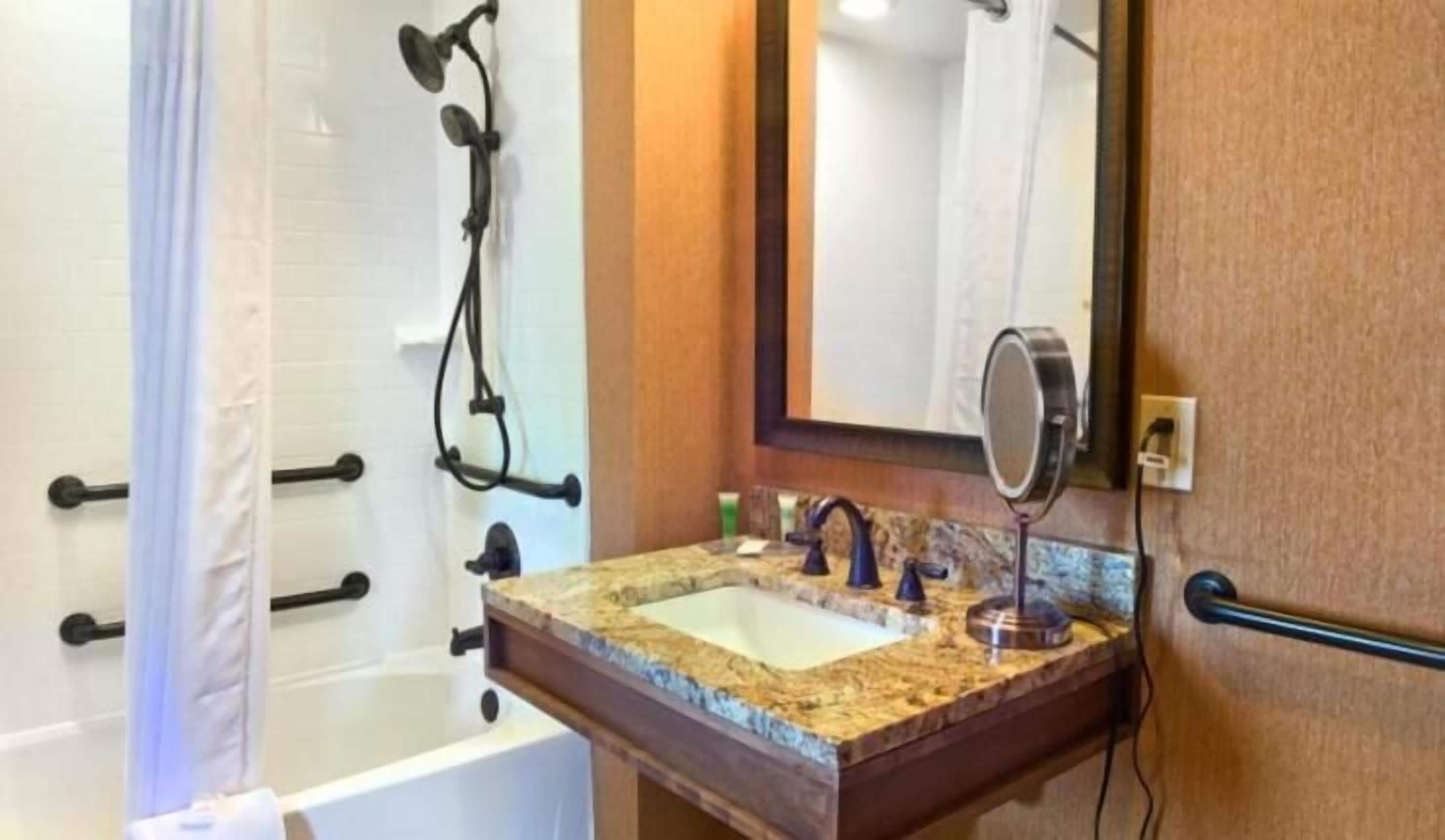 Ein Badezimmer mit einer Badewanne, einem Waschbecken mit Spiegel und einer Duschkabine.