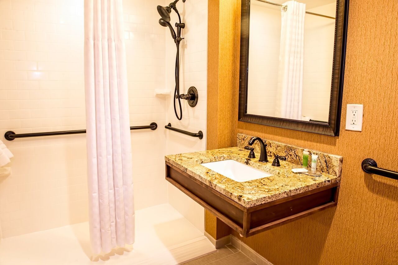A bathroom with a shower, a sink with a mirror, and a towel rack.