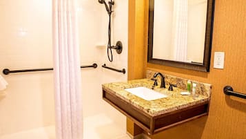 A bathroom with a shower, a sink with a mirror, and a towel rack.