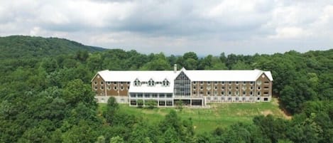 A large, multi-story building with a symmetrical facade, surrounded by dense forest.