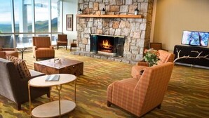 A cozy lounge area with a stone fireplace, comfortable seating, and a large window offering a scenic view.