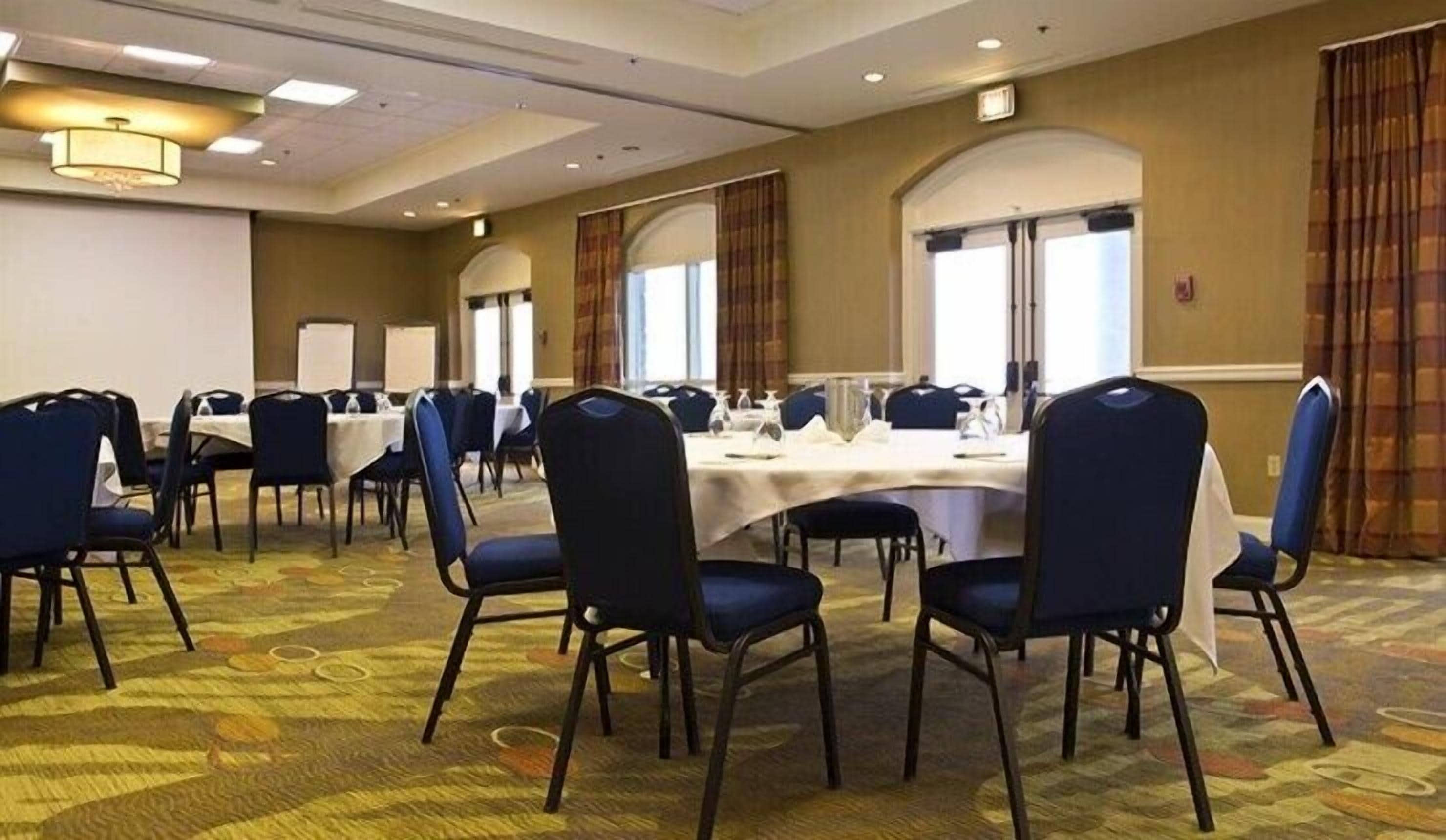 A conference room with round tables, blue chairs, and a carpeted floor.