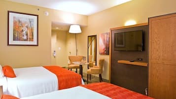 A hotel room with two beds, a television, a desk with a chair, and artwork on the walls.