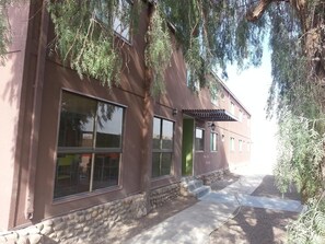A building with large windows, a stone base, and a covered entrance. - Juku Hostal (Calama)
