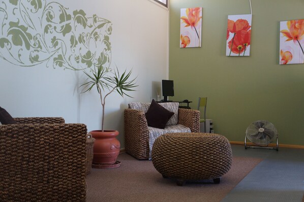 A cozy living room with a sofa, ottoman, and a potted plant. - Juku Hostal (Calama)