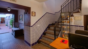 A staircase with patterned tiles, a wooden desk with a computer, and a view of the outside. - Al-mudawar (Almodovar del Rio)