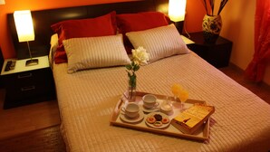 A neatly made bed with a tray of breakfast items, including toast, eggs, and a book, in a warmly lit room. - Al-mudawar (Almodovar del Rio)