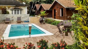 Area piscina con una vasca rettangolare, lettini e un solarium in legno.