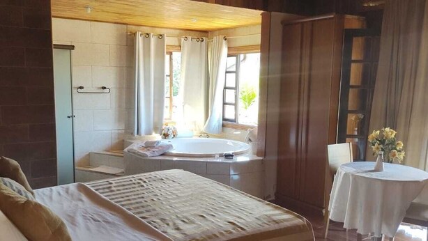 Un'ampia camera da letto con un letto grande, un tavolino e una finestra con tende.