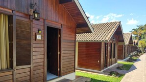 Una fila di cabine di legno con tetto in tegole, un vialetto lastricato e un piccolo giardino.