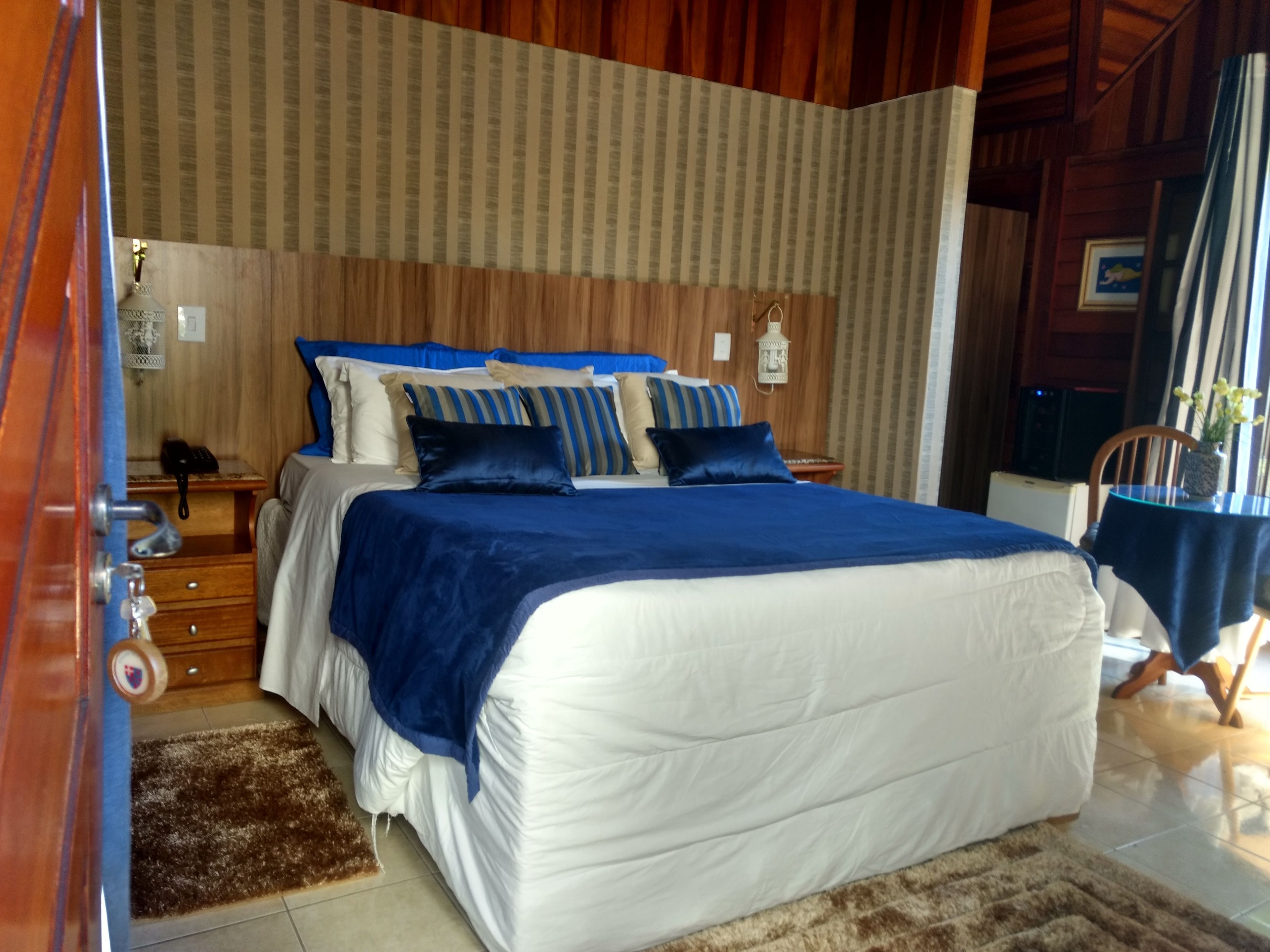 A bedroom with a large bed, wooden headboard, and a nightstand with a lamp.