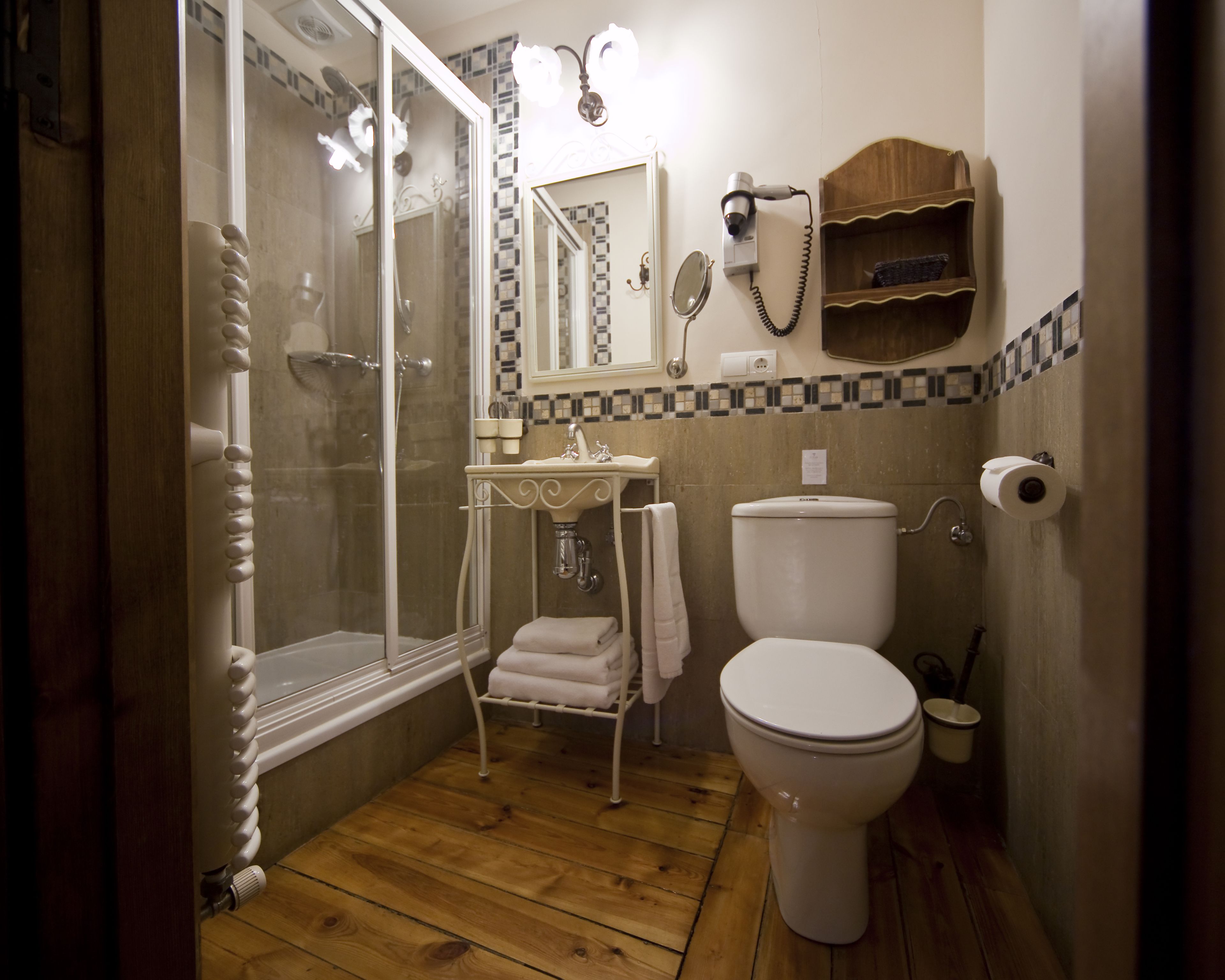 A bathroom with a shower, toilet, sink, and a mirror.