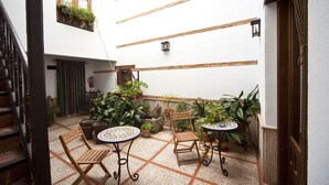 A courtyard with a tiled floor, wooden furniture, and potted plants. - La Morada de Juan de Vargas (Villanueva de los Infantes)