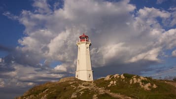 Un faro en una colina rocosa con cielo despejado y nubes.