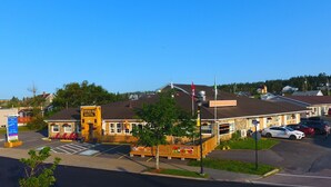 A motel with a prominent sign, outdoor seating, and a parking lot. - Fortress Inn Louisbourg (Louisbourg)