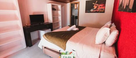 A bedroom with a bed, a desk, a television, and a mirror.