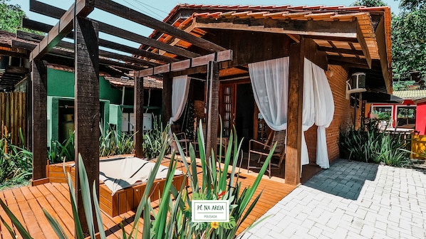 Una estructura de madera con un patio cubierto, una terraza de madera y un letrero que dice "Pé Na Areia Pousada".
