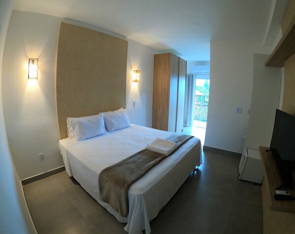 Habitación de hotel con una cama grande, dos lámparas de noche, un televisor y vistas al exterior.