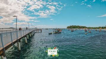 Um cais que se estende sobre a água, com barcos e uma ilha ao longe.