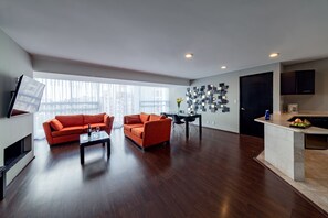 A modern living room with two orange sofas, a coffee table, and a dining area with a black table and chairs.