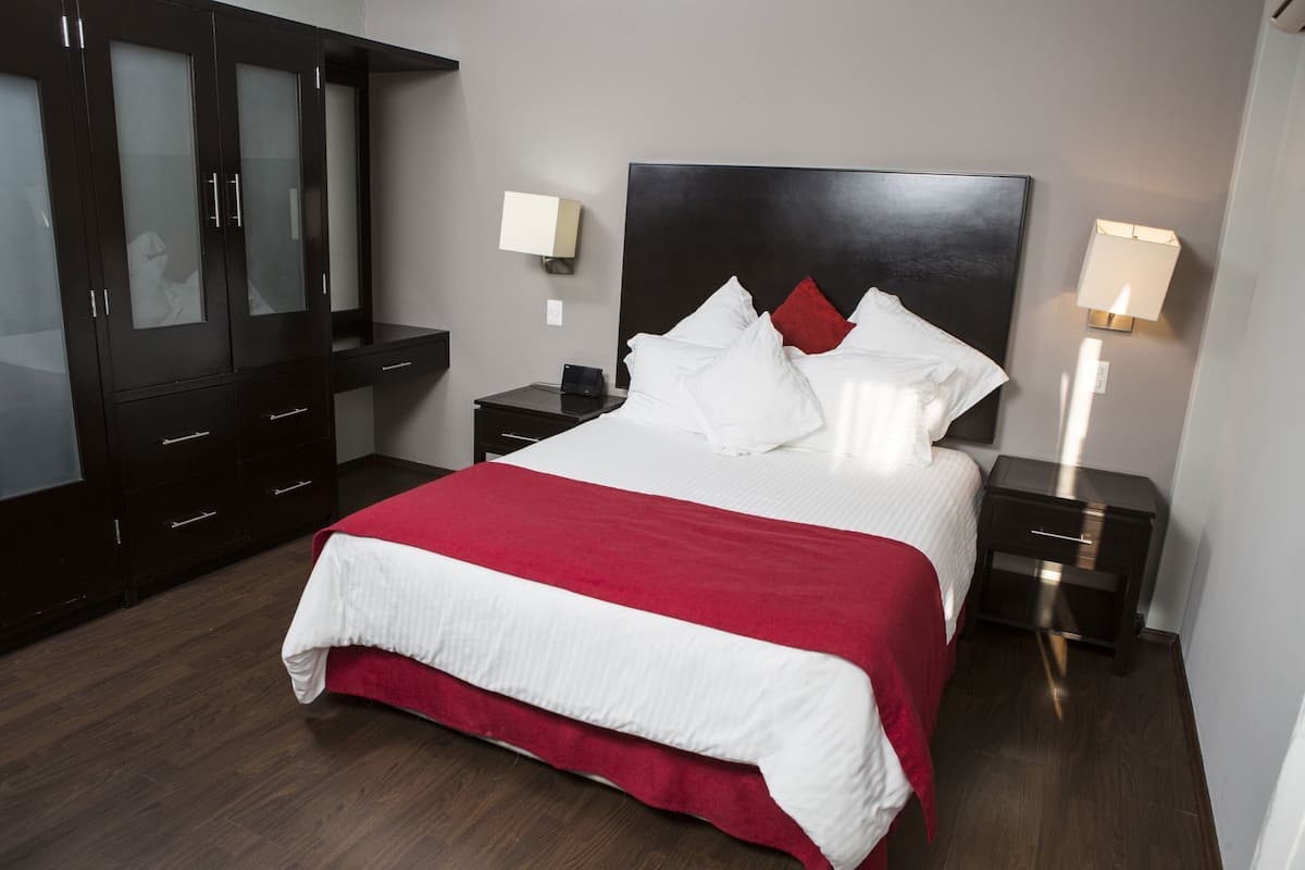 Ein Hotelzimmer mit Bett, Schrank, Nachttischen und einem Nachtlicht.
