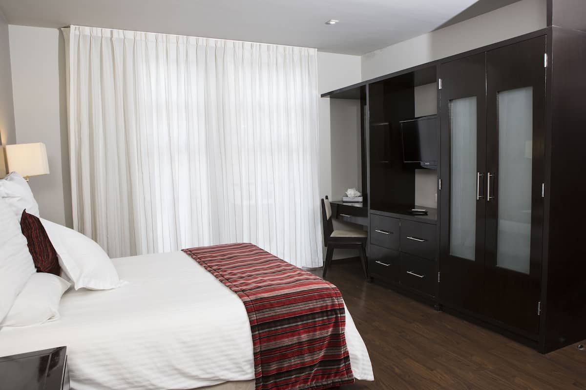 Ein Hotelzimmer mit Bett, Schreibtisch, Kleiderschrank und Fernseher.
