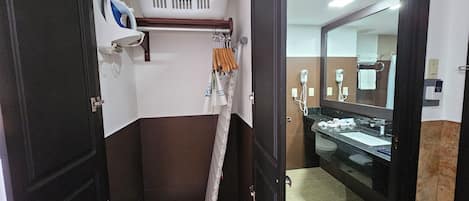 Un baño con ducha, un espejo, toallero y un estante pequeño con secador de pelo.